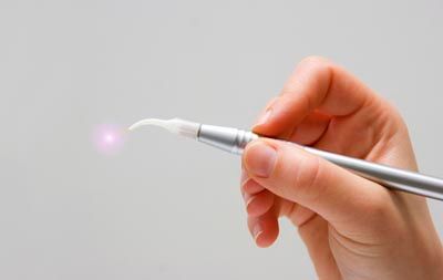 Dental laser handpiece emitting light during a treatment